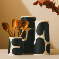 three black and white cups with wooden spoons in them