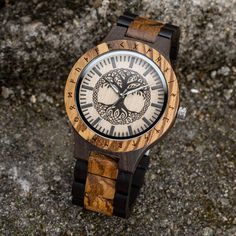 Experience the merging of art, nature, and timekeeping with our mesmerizing Tree of Life Yggdrasil Wooden Watch.  This exquisite timepiece showcases a stunning Yggdrasil tree on its wooden face, capturing the essence of strength and wisdom. The watch's wooden construction, combined with its intricate design, creates a visually captivating accessory that is sure to make a statement.  With its precise Japanese quartz movement and adjustable band, this watch offers both style and functionality.  Each watch is carefully made with utmost attention to detail, resulting in a unique and high quality piece that is as exceptional as the legend it represents.  Take a piece of ancient mythology with you wherever you go with our Tree of Life Yggdrasil Wooden Watch. Unique, high-quality wooden watch, en Engraved Brown Watches For Gift, Engraved Brown Watches As Gift, Engraved Brown Watches For Gifts, Brown Engraved Watch For Gift, Brown Engraved Watches As Gifts, Analog Jewelry And Watches With Round Dial For Gifts, Compass Design Watch With Round Dial For Gift, Round Dial Compass Watch As Gift, Compass Design Watch With Round Dial