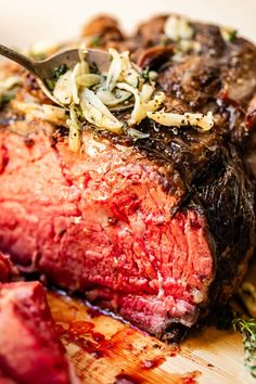 a piece of meat is being cut up on a cutting board with a knife and fork