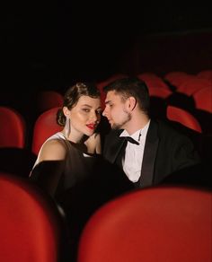 a man and woman are sitting in an empty theater seat looking at each other's eyes