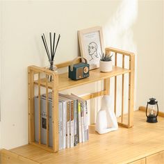 a wooden table topped with books next to a white wall and a plant on top of it