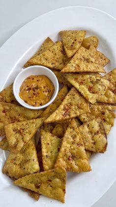 a white plate topped with tortilla chips and dipping sauce