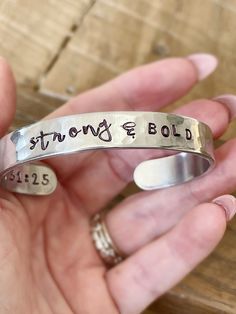 Introducing the Uplift Collection featuring hand stamped metal cuff bracelets with encouraging reminders of who you and whose you and scripture reference. Choose one bracelet: 1. STRONG & BOLD 3/8" CUFF 2. BEAUTIFUL WARRIOR 1/2" CUFF 3. GRACIOUS & KIND 1/4" CUFF 4. MADE WORTHY 1/2" CUFF 5. VICTORIOUS 3/8" CUFF 6. CHOSEN & KNOWN 1/4" CUFF Each bracelet has a scripture reference written on the inside of the cuff. Add a leather wrap bracelet here: https://etsy.me/3koMuWo Add a Rhinestone Bracelet h Inspirational Personalized Faith Name Bracelet, Personalized Inspirational Cuff Bracelet For Everyday, Everyday Personalized Meaningful Cuff Bracelet, Personalized Everyday Meaningful Cuff Bracelet, Everyday Inspirational Personalized Cuff Bracelet, Meaningful Hand Stamped Cuff Bangle, Personalized Inspirational Cuff Bracelet Gift, Inspirational Personalized Cuff Bracelet Gift, Inspirational Personalized Cuff Bracelet For Gifts