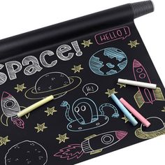 a blackboard with space drawings on it and three crayons next to it