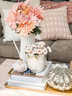 a coffee table with flowers and books on it in front of a couches pillows