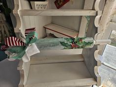 an old white shelf with christmas decorations on it and ribbons tied to the top, in front of a window