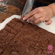 a woman is cutting into some brownies on a sheet of paper with a knife