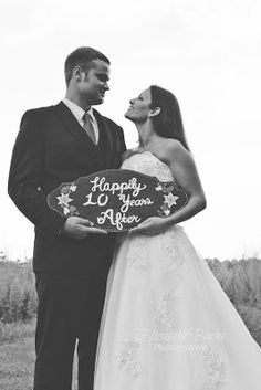 a man and woman standing next to each other holding a sign that says happily anniversary after