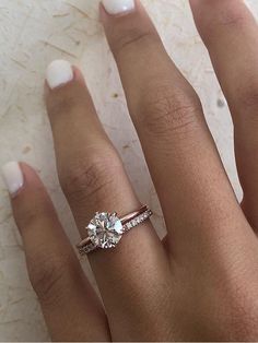 a woman's hand with a diamond ring on top of her finger and white nail polish