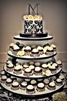 a three tiered cake with cupcakes on the bottom is decorated with black and white icing