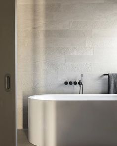 a white bath tub sitting in a bathroom next to a wall mounted faucet