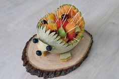 a dragon fruit carving sitting on top of a piece of wood with toothpicks in it's mouth