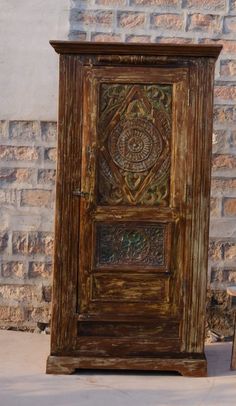 an old wooden cabinet sitting in front of a brick wall