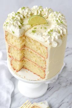 a slice of cake with white frosting and lime on the top is being cut by a fork