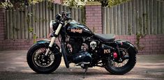 a black motorcycle parked in front of a brick wall