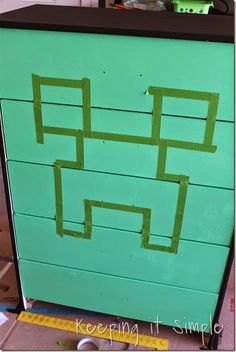 a green dresser with some tape on it's sides and the top painted like a pacman