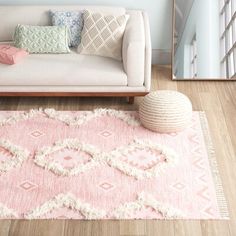 a living room with a couch, rug and mirror on the wall in front of it