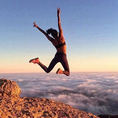 a woman jumping in the air on top of a mountain