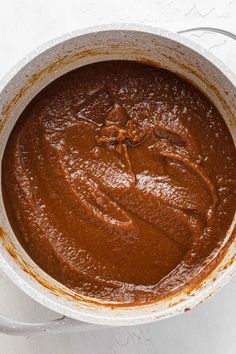 a pot filled with brown sauce on top of a white table