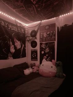 a bedroom decorated in pink and black with posters on the wall, lights strung from the ceiling