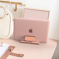 an apple laptop computer sitting on top of a desk next to a purse and other items