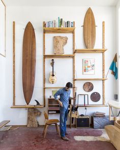 a man standing in front of a wooden shelf filled with surfboards and other items