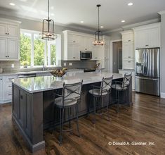 a large kitchen with white cabinets and wooden floors