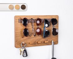 a wooden board with sunglasses and keys hanging from it's hooks on the wall