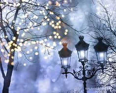 three street lamps are lit up in the night sky with boket lights behind them