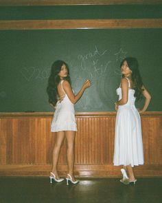 two young women standing in front of a chalkboard