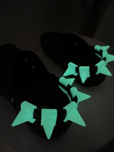 pair of black slippers with green and white stars on the soles in dark room