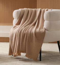 a white chair with a tan blanket on it