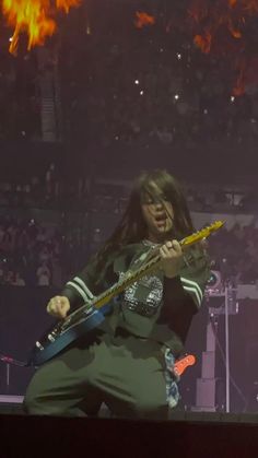 a woman with long hair playing an electric guitar in front of a crowd at a concert