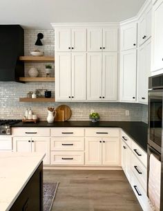 a kitchen with white cabinets and black counter tops