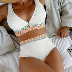 a woman laying on top of a bed wearing a white bikinisuit and straw hat