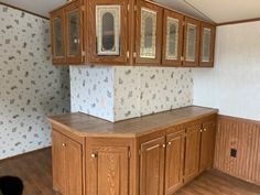 an empty kitchen with wooden cabinets and wood flooring in the background is a wallpapered wall