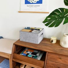 a wooden table topped with drawers next to a potted plant and a poster on the wall