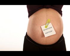 a pregnant woman's belly with a note pinned to it that says eviction notice