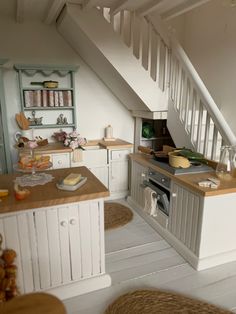 a kitchen with an oven, sink and stairs in the back ground is seen from across the room