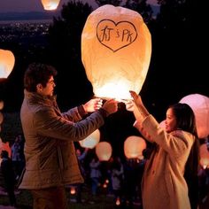 two people releasing lanterns into the sky