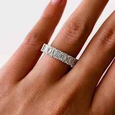 a woman's hand with a diamond ring on her left hand, showing the band