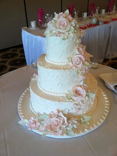 a three tiered wedding cake with pink flowers on the top and bottom, sitting on a table