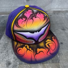 a purple and yellow hat with an image of a shark on it's side