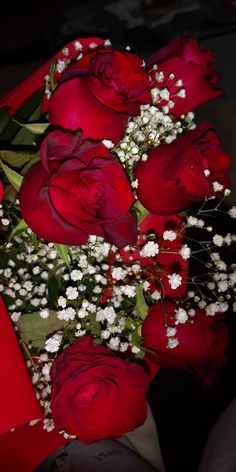 a bouquet of red roses with baby's breath in the middle and white flowers