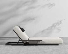 a black and white chair sitting on top of a cement floor next to a wall