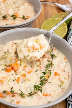 two bowls filled with soup and garnished with fresh herbs, limes, and sour cream