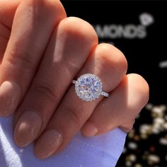 a woman's hand holding an engagement ring with a diamond center in the middle