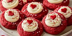 red velvet cookies with white frosting and hearts on top are arranged on a plate