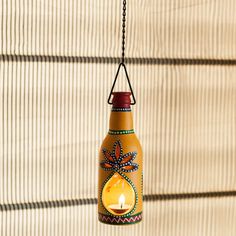 a candle hanging from a chain with a glass bottle in the shape of a flower