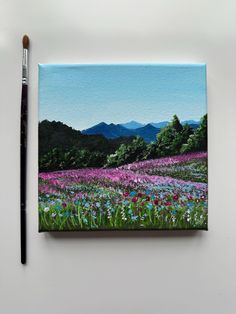 a painting of a field with flowers and mountains in the background